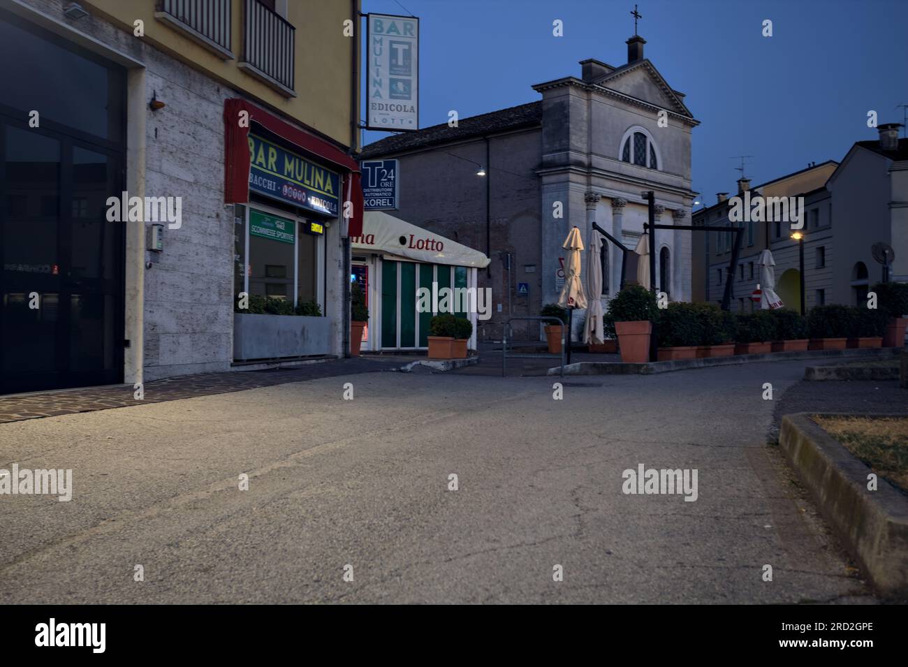 Bürgersteig vor einer Gruppe von Gebäuden und Schaufenster in einer italienischen Stadt in der Abenddämmerung Stockfoto