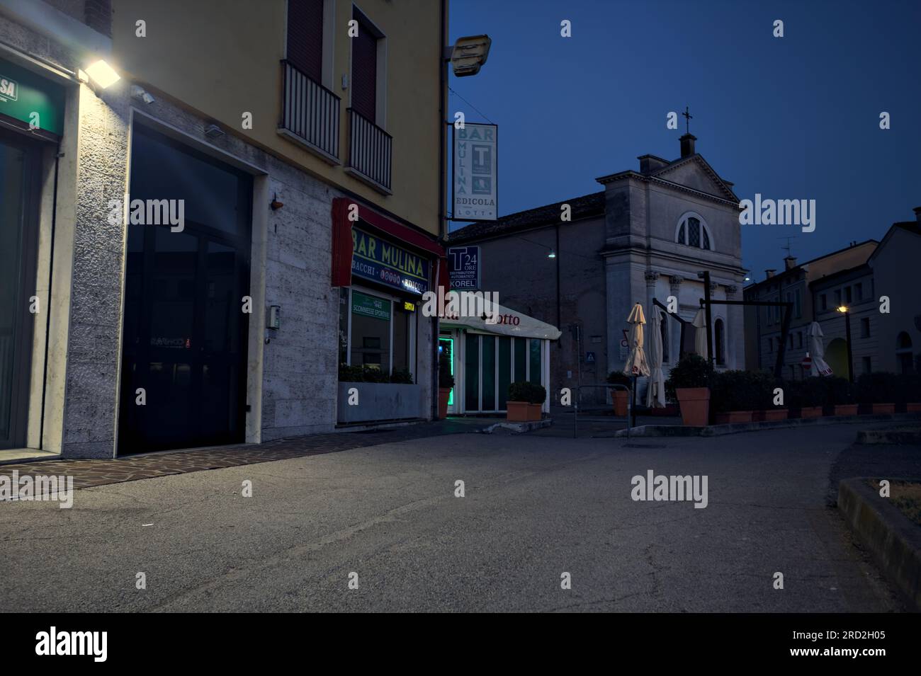 Bürgersteig vor einer Gruppe von Gebäuden und Schaufenster in einer italienischen Stadt in der Abenddämmerung Stockfoto