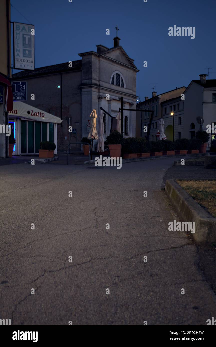 Bürgersteig vor einer Gruppe von Gebäuden und Schaufenster in einer italienischen Stadt in der Abenddämmerung Stockfoto