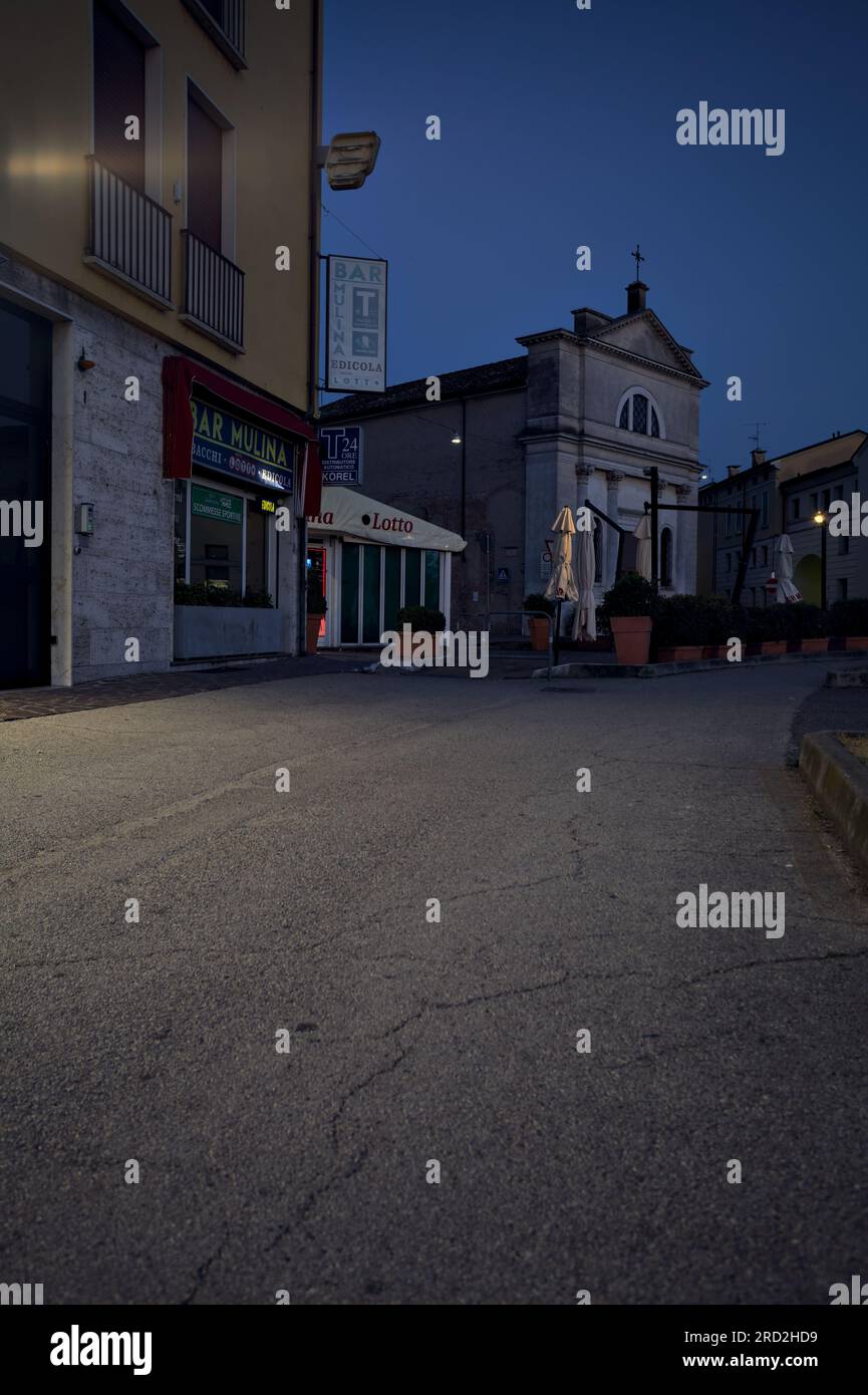 Bürgersteig vor einer Gruppe von Gebäuden und Schaufenster in einer italienischen Stadt in der Abenddämmerung Stockfoto