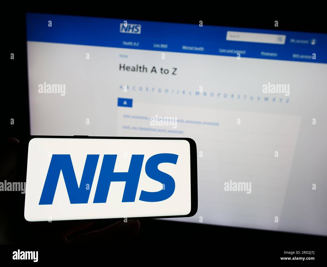 Person, die ein Smartphone mit dem Logo des British National Health Service (NHS) auf dem Bildschirm vor der Website hält. Konzentrieren Sie sich auf das Display des Telefons. Stockfoto