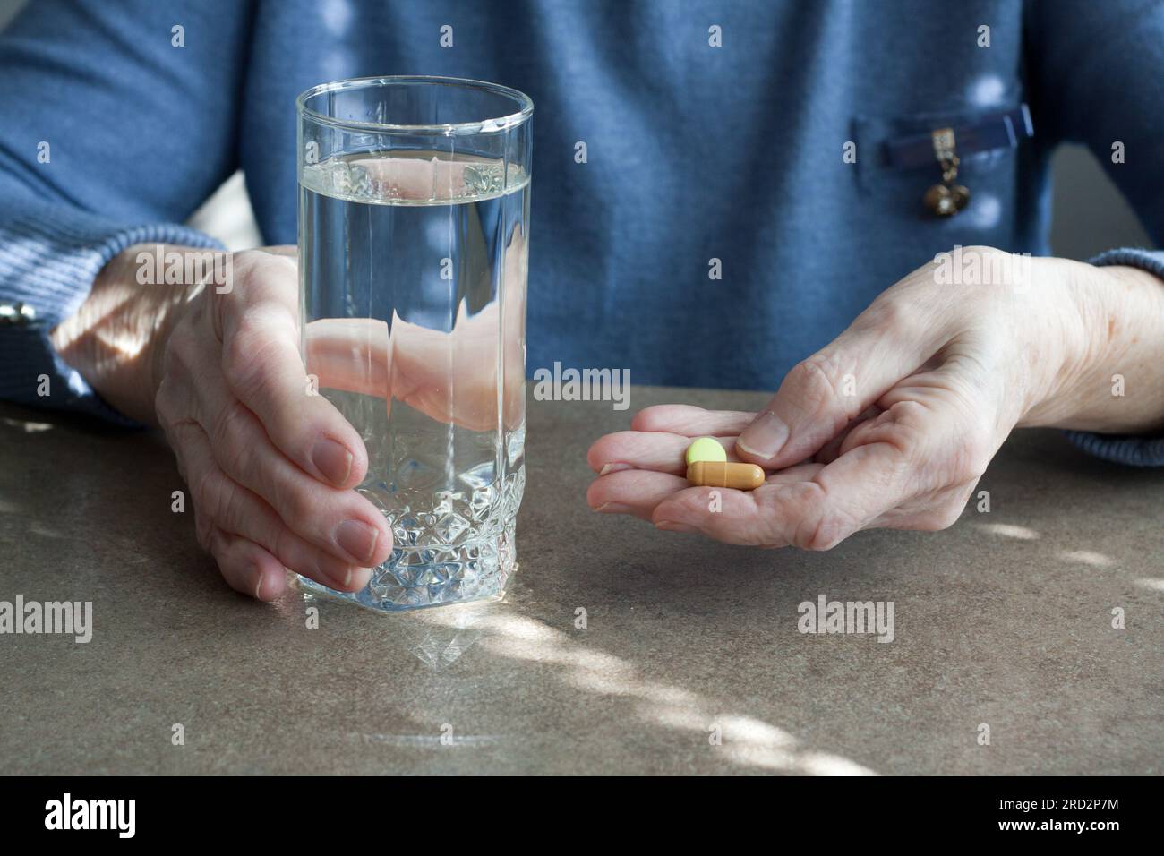 Nahaufnahme von älteren Frauen mit Hand-haltenden Pillen und einem Glas Trinkwasser. Seniorin wird Medikamente gegen Krankheiten einnehmen. Gesundheitsprobleme im Alter Stockfoto