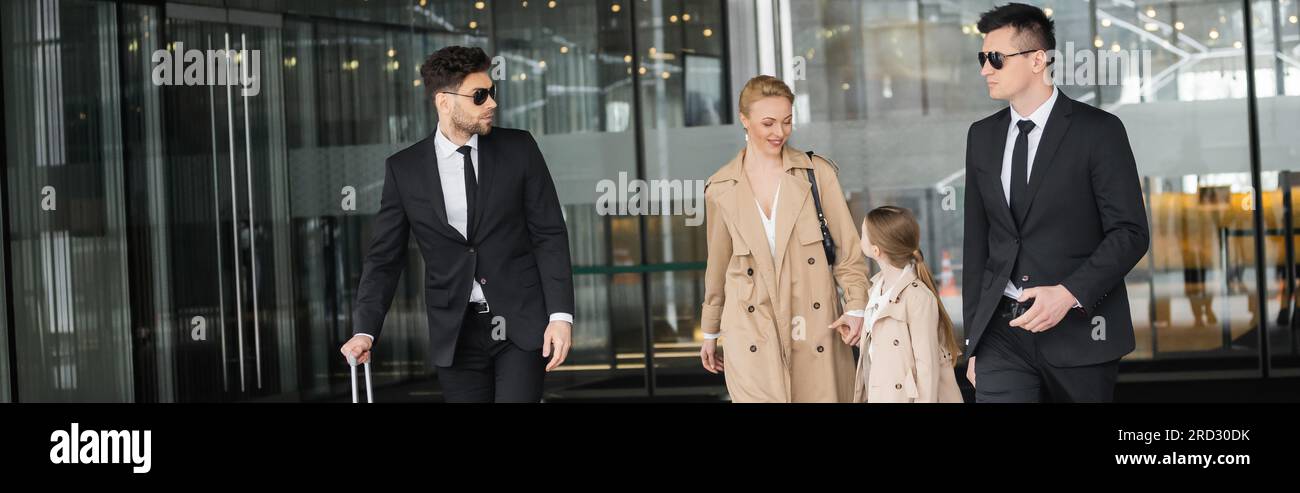 Leibwächter schützen die Privatsphäre weiblicher Klienten, Frau und Tochter, die das Hotel auf unscharfem Hintergrund verlassen, persönliche Sicherheit der reichen Familie, ich Stockfoto