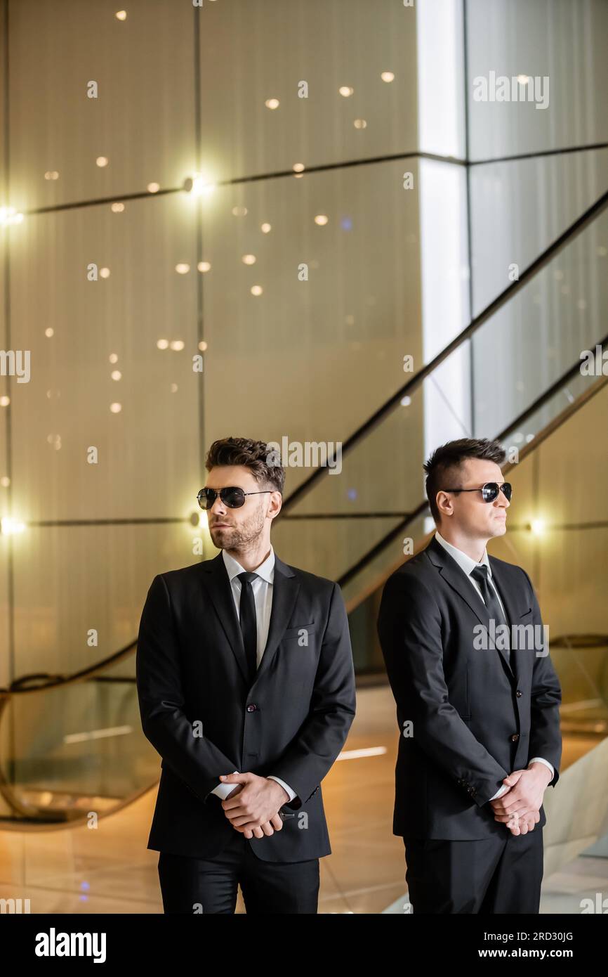 Sicherheitsmanagement von Luxushotels, gutaussehenden Männern in formeller Kleidung und Sonnenbrille, Leibwächtern im Dienst, Sicherheitsmaßnahmen, Wachsamkeit, Anzüge und Krawatten, priva Stockfoto