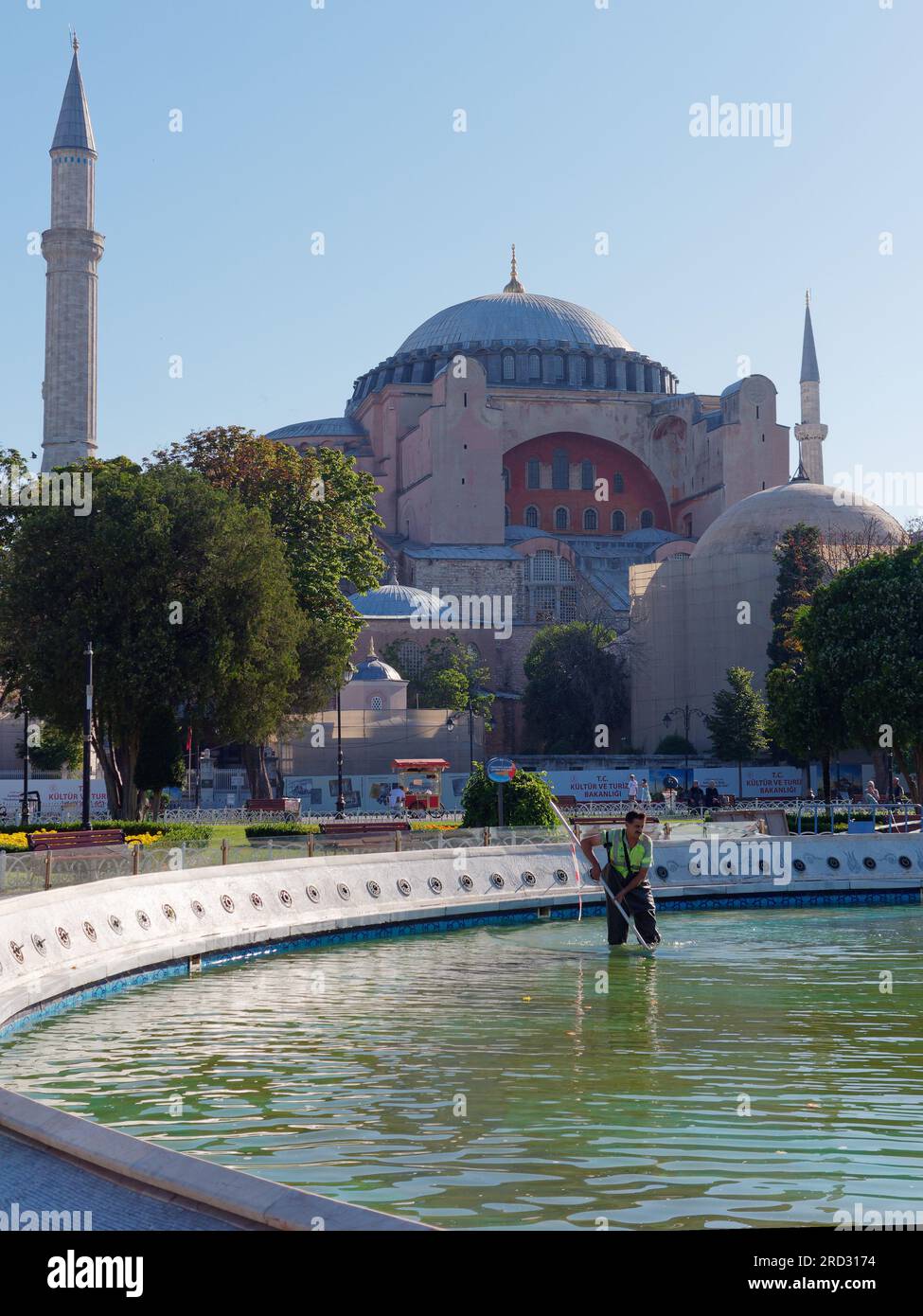 Arbeiter, die an einem Sommermorgen ein Wasserspiel mit der Hagia Sophia Moschee im Sultanahmet Park reinigen, Istanbul, Türkei Stockfoto
