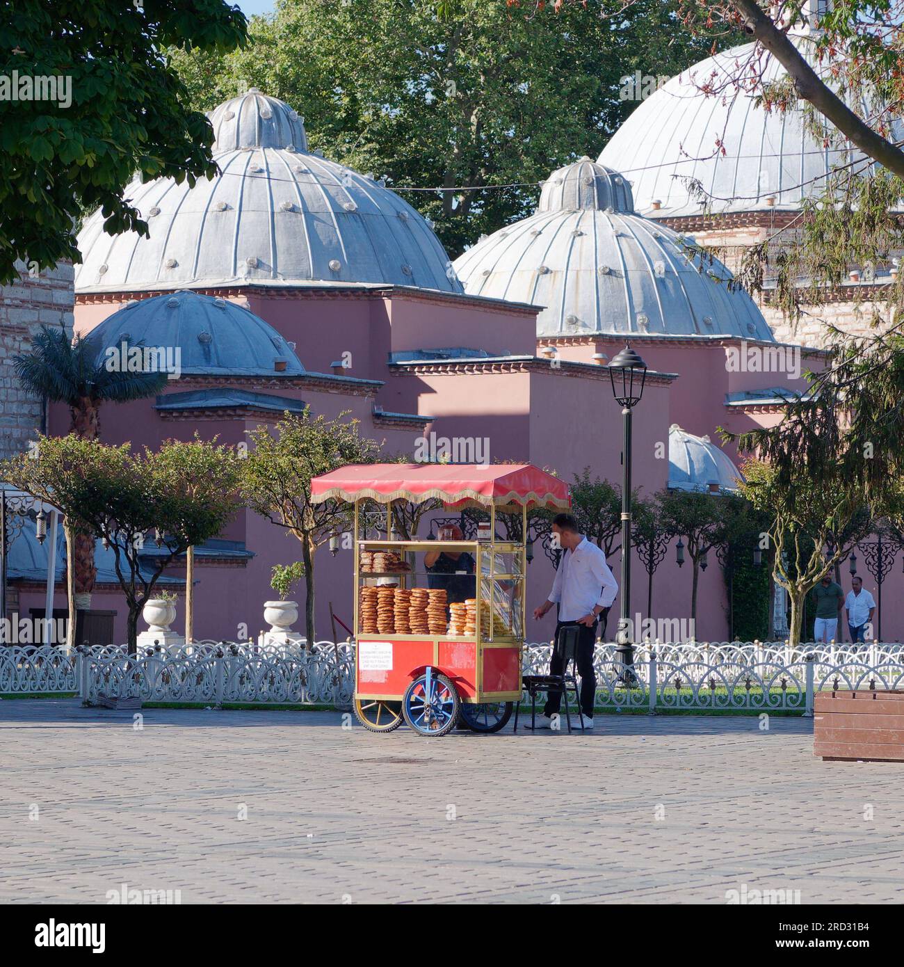 Hurrem Sultan Hammam türkisches Badehaus im Sultanahmet Park in Istanbul, Türkei, mit einem roten Verkaufswagen, in dem Simits auch türkische Bagels verkauft werden. Stockfoto