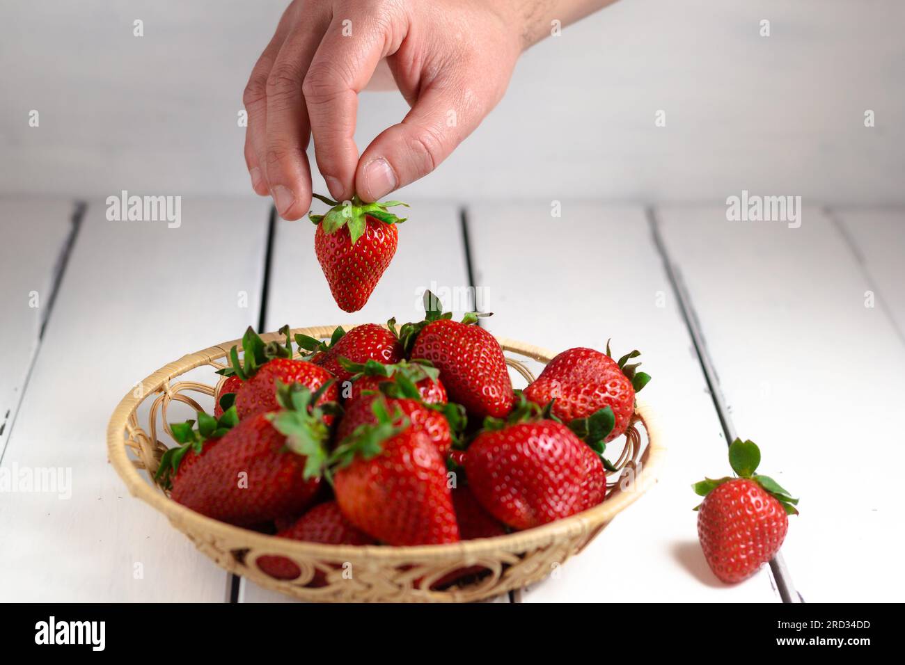 Eine Hand mit einer Erdbeere, isoliert auf weißem Hintergrund. Schließen. Stockfoto