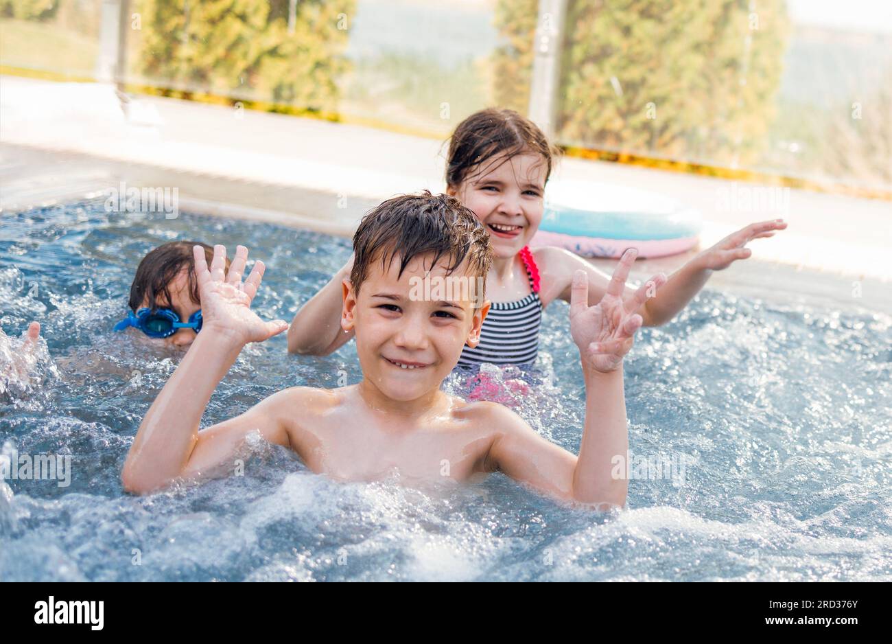 Drei kleine Kinder schwimmen im Außenpool. Süße Kinder kuscheln und