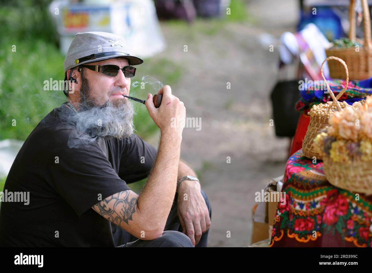 Ein Straßenverkäufer in den USA, eine alte Konföderierten-Mütze, die Pfeife raucht und Souvenirs verkauft. Stockfoto