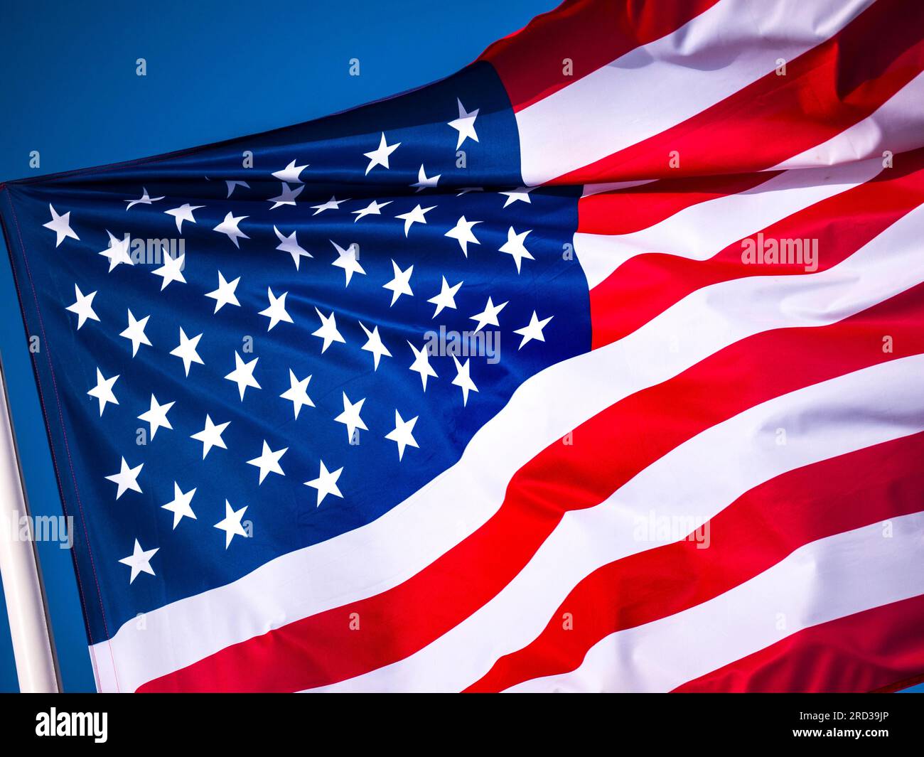 Stars & Stripes American Flag in Aktion, die aus nächster Nähe aufhält und in einer Brise mit sonnigem blauen Himmel hinter den USA weht Stockfoto