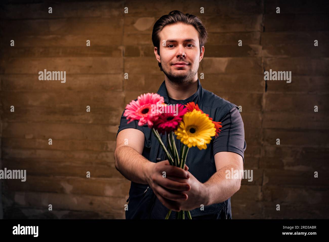 Junger, gutaussehender, positiver Mann, der einen Blumenstrauß gibt Stockfoto