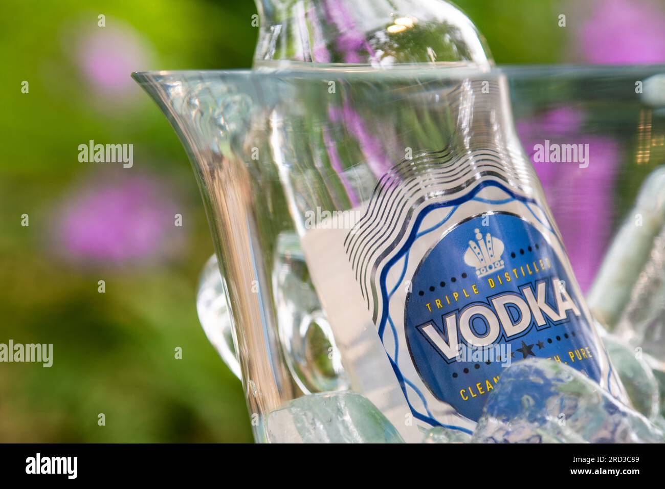 Wodka Flasche auf Eis im Crystal Getränke Kühler im späten Sommer Sonne auf Alfresco Blumengarten Terrasse Tisch Stockfoto