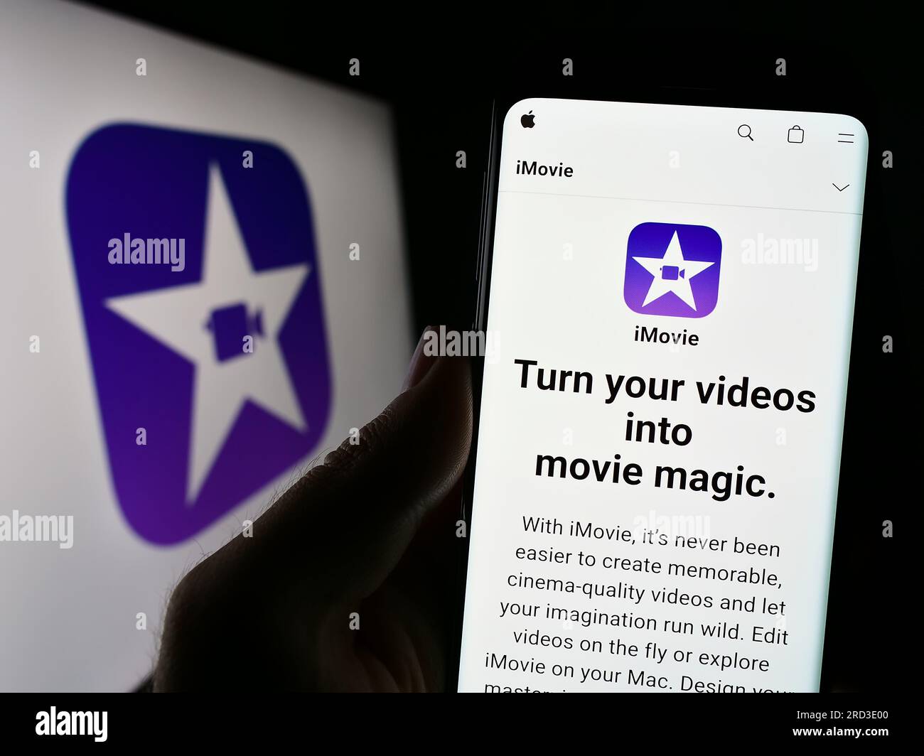 Person, die ein Mobiltelefon mit einer Website der Videobearbeitungssoftware iMovie (Apple Inc.) auf dem Bildschirm vor dem Logo hält. Konzentrieren Sie sich auf die Mitte des Telefondisplays. Stockfoto