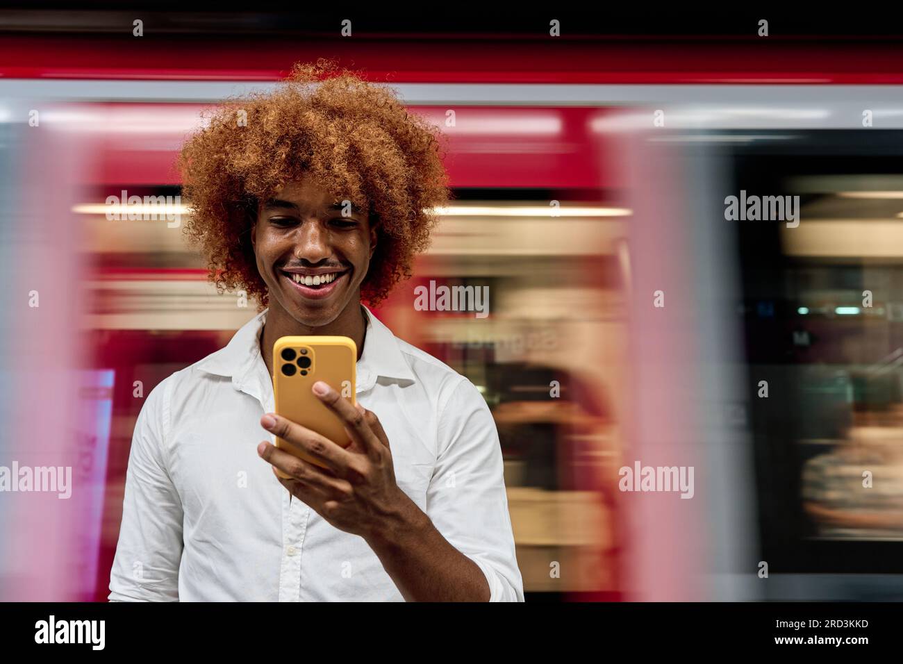 Junger afroamerikanischer Mann, der in Subway mit einem Smartphone steht Stockfoto