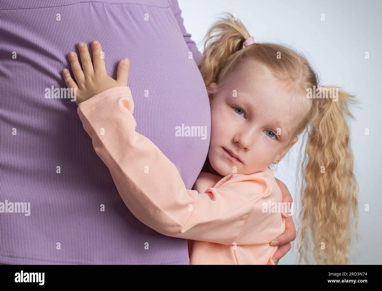 Die Tochter umarmt den großen Bauch der schwangeren Mutter in Erwartung der Geburt ihres Bruders. Stockfoto