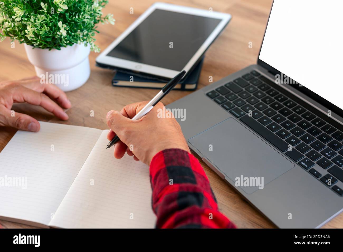 Schüler verwendet Laptop und schreibt Notizen. Stockfoto