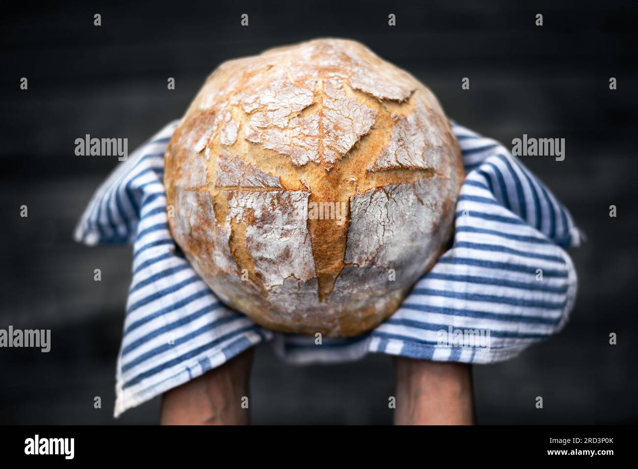 Traditionelles Sauerteig-Brot in Bäckerhand auf einem rustikalen Holztisch. Fotos von gesunden Lebensmitteln Stockfoto