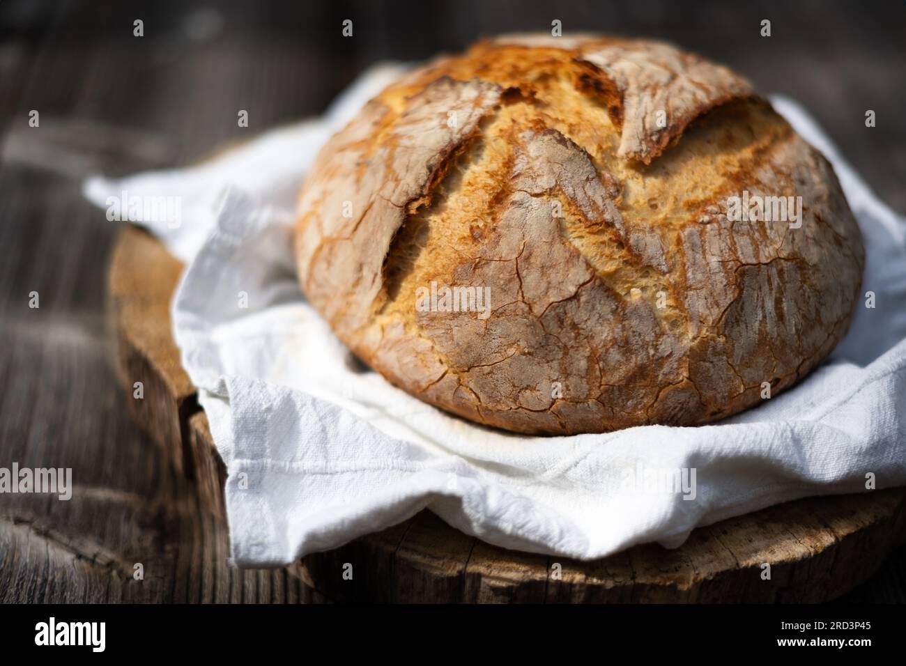 Traditionelles Sauerteig-Brot mit roughiger Schale auf einem rustikalen Holztisch. Fotos von gesunden Lebensmitteln Stockfoto