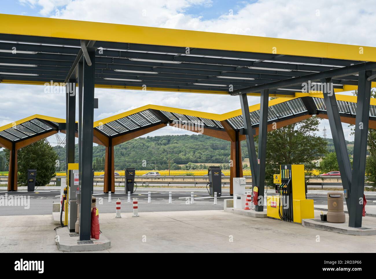 FRANKREICH, Tankstelle und Schnellladestation für Elektrofahrzeuge an der Autobahn, Solarzellen auf dem Dach / FRANKREICH, Dyneff Tankstelle und Fastned Stromladestation für Elektrofahrzeuge an der Autobahn, Solarzellen auf Dach, Hintergrund Sonnenblume Feld Stockfoto