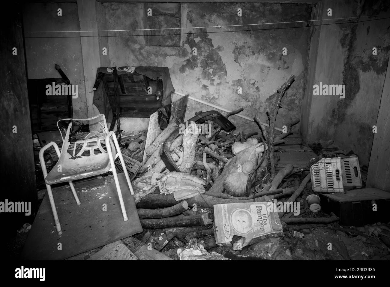 Ein Zimmer in einem heruntergekommenen Haus voller Schutt, kaputte Möbel und allgemeinen Hausmüll. Ein Schwarzweißbild. Stockfoto