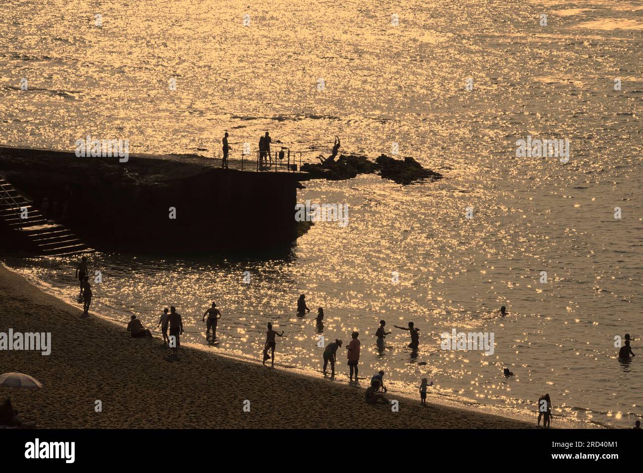 Biarritz, Frankreich, Juli, 2023 Schwimmer und Taucher genießen den Glanz eines frühen Sommeruntergangs auf der Plage du Port Vieux, Biarritz, Frankreich Stockfoto