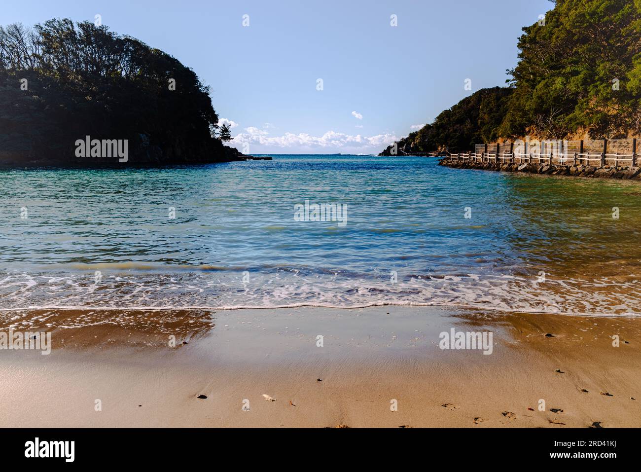 Am Anfang der Suzaki Promenade befindet sich dieser malerische kleine Strand in einer Tanoura Cove. Ich liebe den Kontrast von weichem braunem Sand und herrlichem Grün Stockfoto