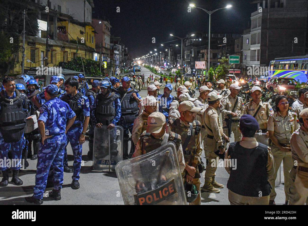 16. Juli 2023, Imphal, Manipur, Indien: Mitarbeiter der Rapid Action Force (L) und Polizisten von Manipur stehen während der Demonstration Wache während einer Straßenblockade durch die Frauenaktivistengruppe Meira Paibi in der Nähe des Viertels Singjamei in Imphal. Die Meira Paibis sind Meitei-Frauen, die aus allen Teilen der Gesellschaft im Imphal-Tal kommen, weithin respektiert werden, eine starke moralische Kraft haben. „Meira“ bedeutet „Licht“ und „Paibi“ bedeutet „Frau“. Diese Frauen sind Teil einer einzigartigen Bewegung namens „Meira Paibi“, die in Manipur entsteht. Und sie haben gegen verschiedene Probleme wie soziale Ungerechtigkeit protestiert Stockfoto