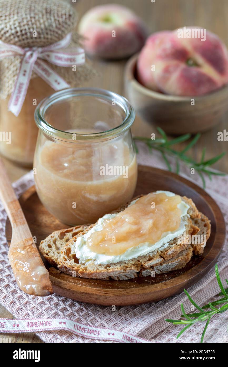 Pfirsichmarmelade auf dem Stück Brot und in einem Glas Stockfoto