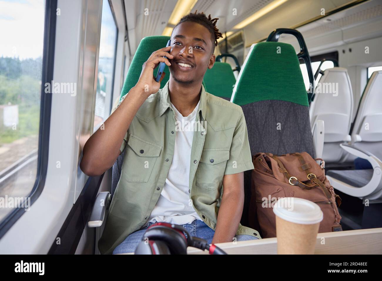 Junger Mann, Der Im Zug Zur Arbeit Pendelt, Im Zug Sitzt Und Mit Dem Handy Spricht Stockfoto
