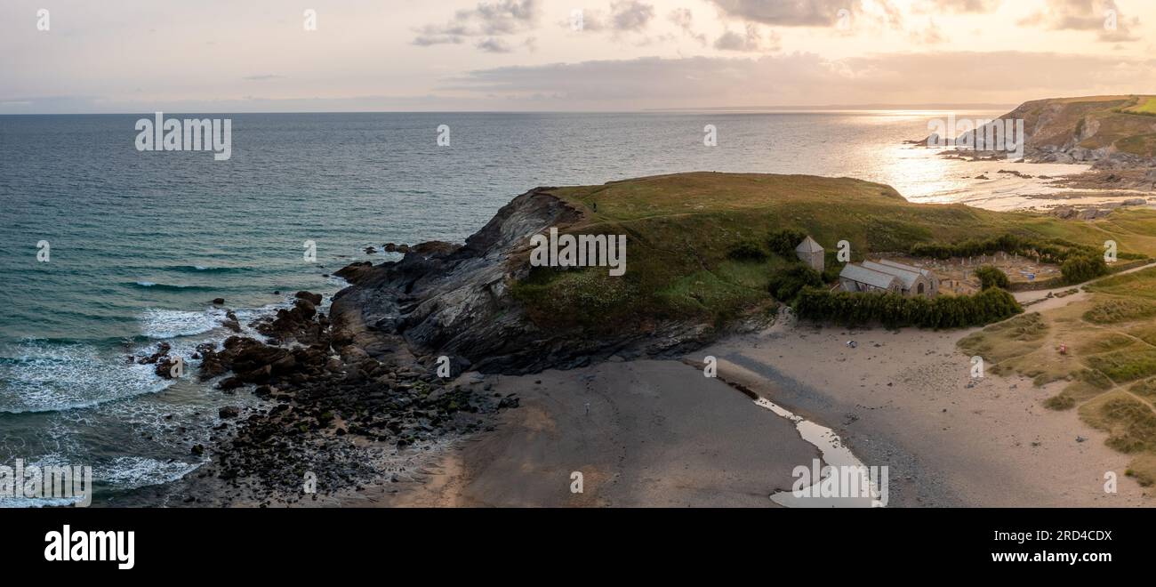 Panoramablick aus der Vogelperspektive auf Church Cove mit seiner historischen Kirche und Dollar Cove bei Sonnenuntergang in Gunwalloe in Cornwall Stockfoto