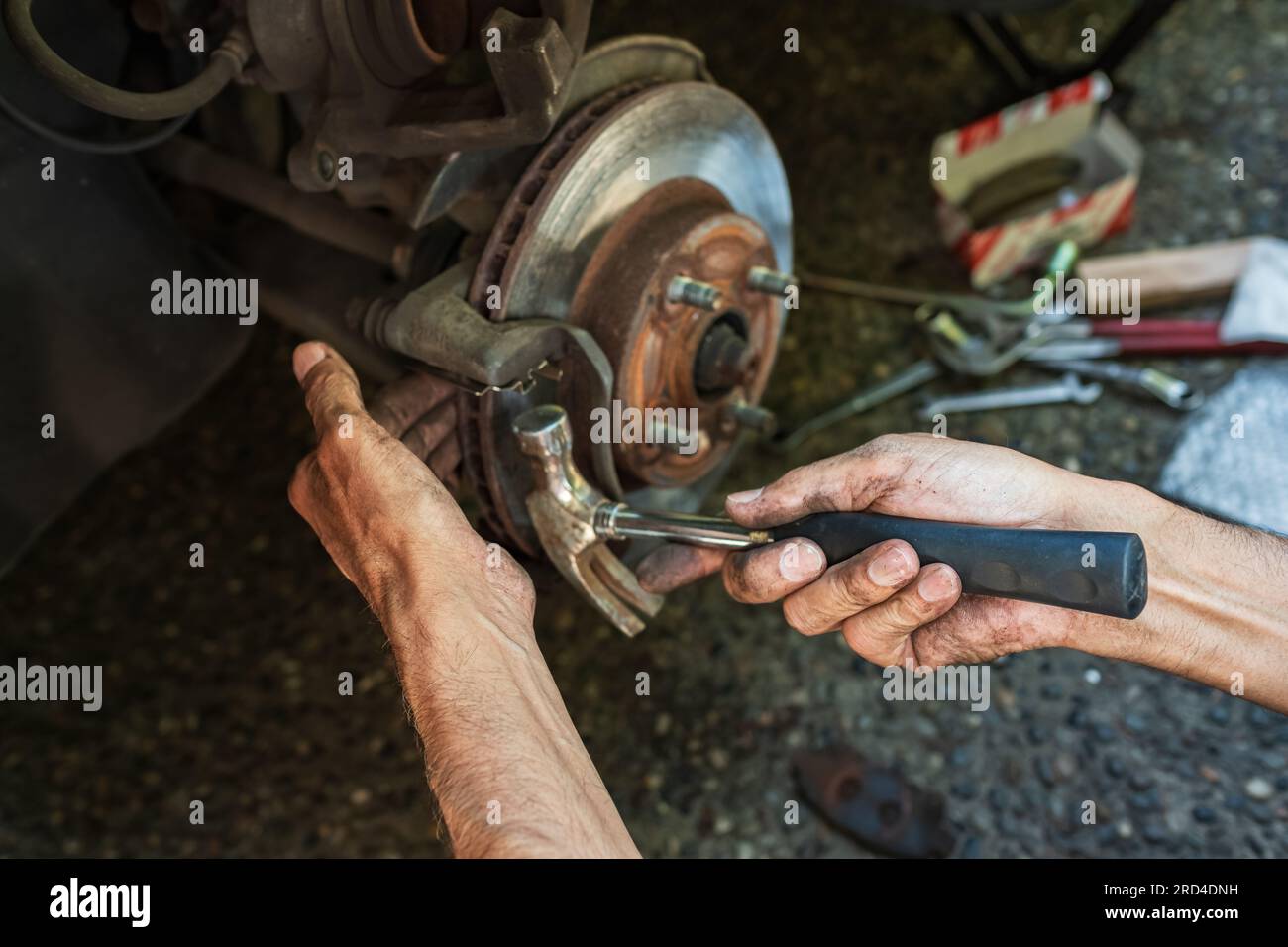 Austausch der Bremsbeläge in Kraftfahrzeugen durch einen Mechaniker. Automechaniker repariert die Bremsen eines Fahrzeugs, Scheibenbremse ohne Räder des Fahrzeugs Stockfoto