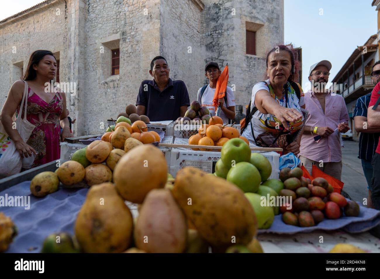 Cartagena, Bolivar, Kolumbien – 17. Februar 2023: Brauner kolumbianischer Frauenführer mit Mikrofon spricht über Obst und Gemüse auf Rädern Stockfoto