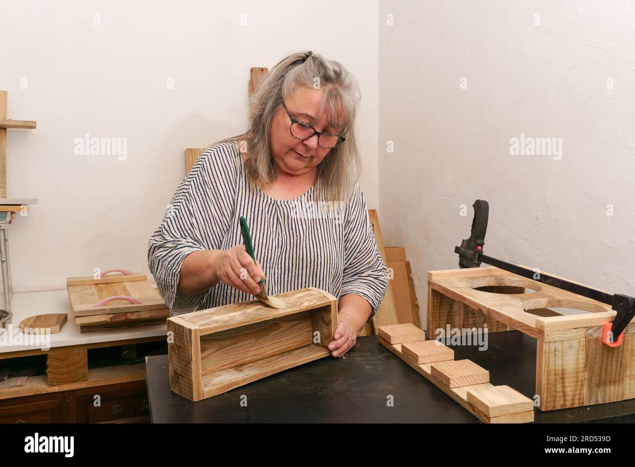 Zimmerlerin malte in seiner Werkstatt eine handgemachte Holzkiste. Konzept der Gleichstellung von Frauen und Männern am Arbeitsplatz Stockfoto