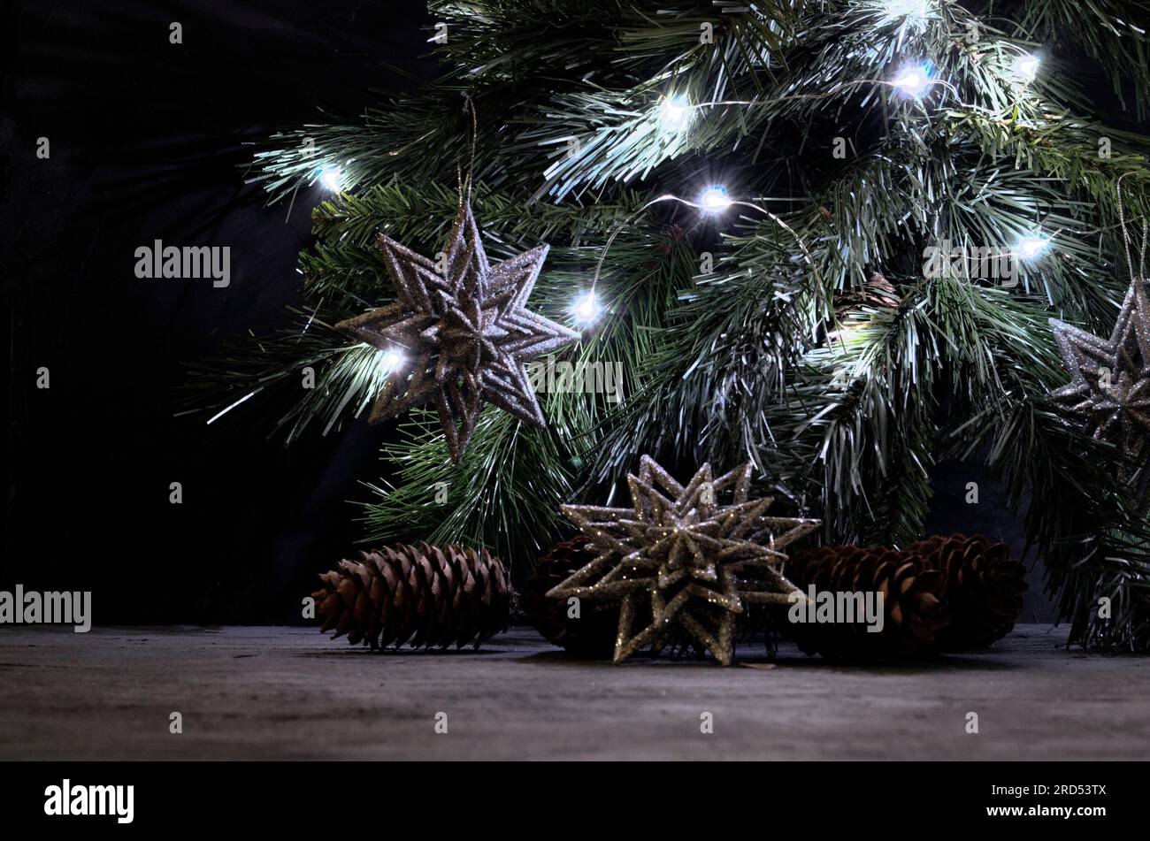 Silberne Schneeflocken, Kiefern und beleuchtete Girlande auf dem Fichtenzweig. Weihnachtsstill-Leben im Vintage-Stil. Grau, Schwarz und Silber Stockfoto
