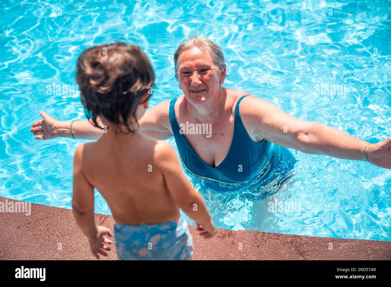 Mutter und Großmutter haben Spaß mit ihrem Enkel im Schwimmbad in den Sommerferien und genießen das Wasser Stockfoto