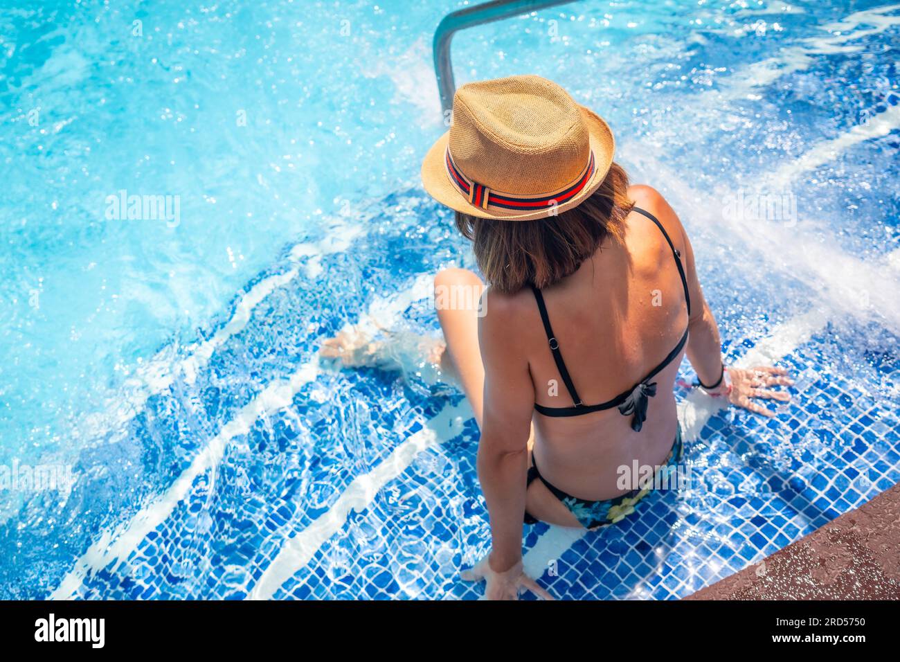 Frau mit Hut im Pool im Spa-Resort im Urlaub. Sommerentspannendes Konzept Stockfoto