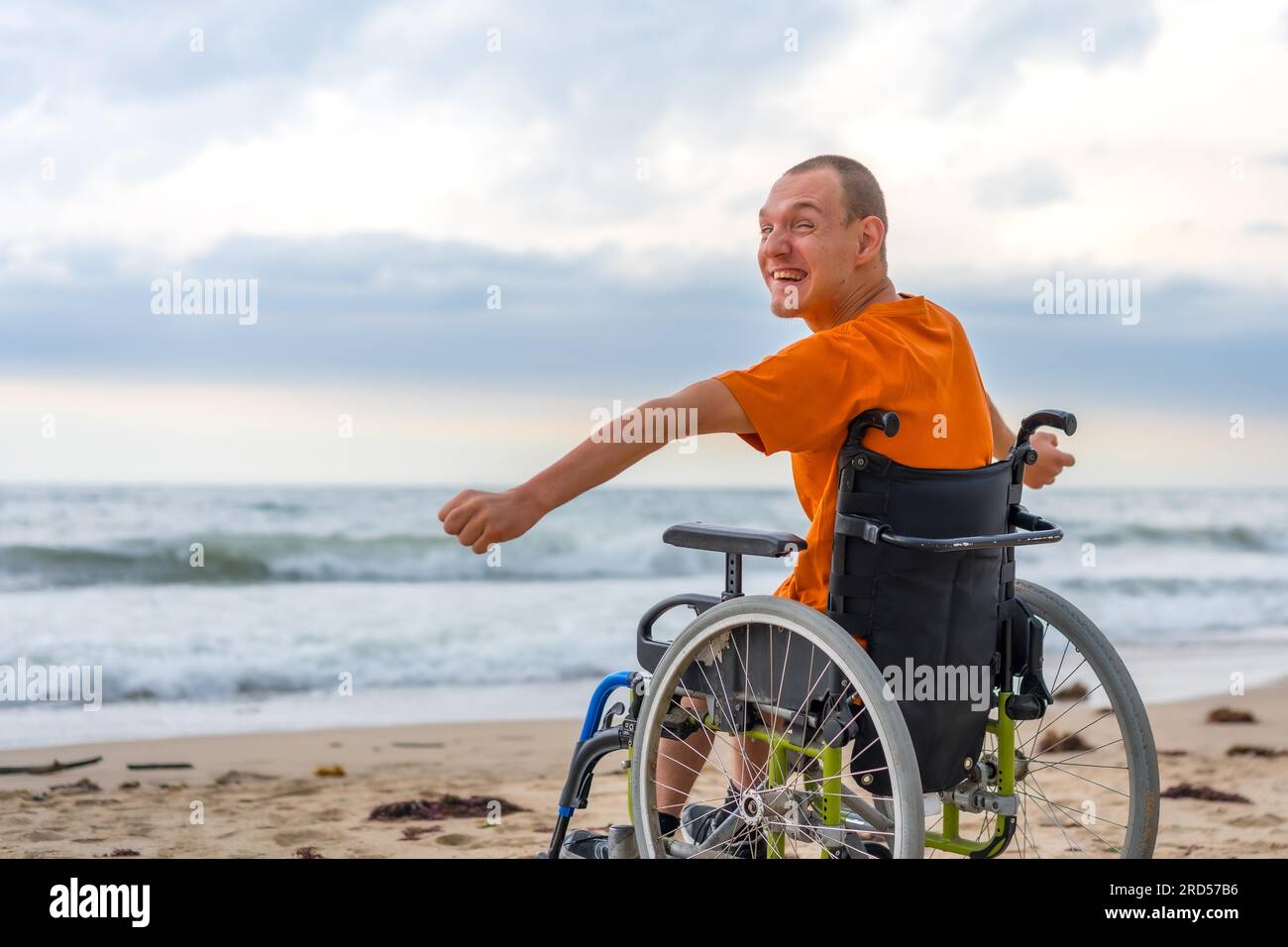 Ein behinderter Mensch auf dem Rücken im Rollstuhl am Strand fühlt sich frei am Meer Stockfoto