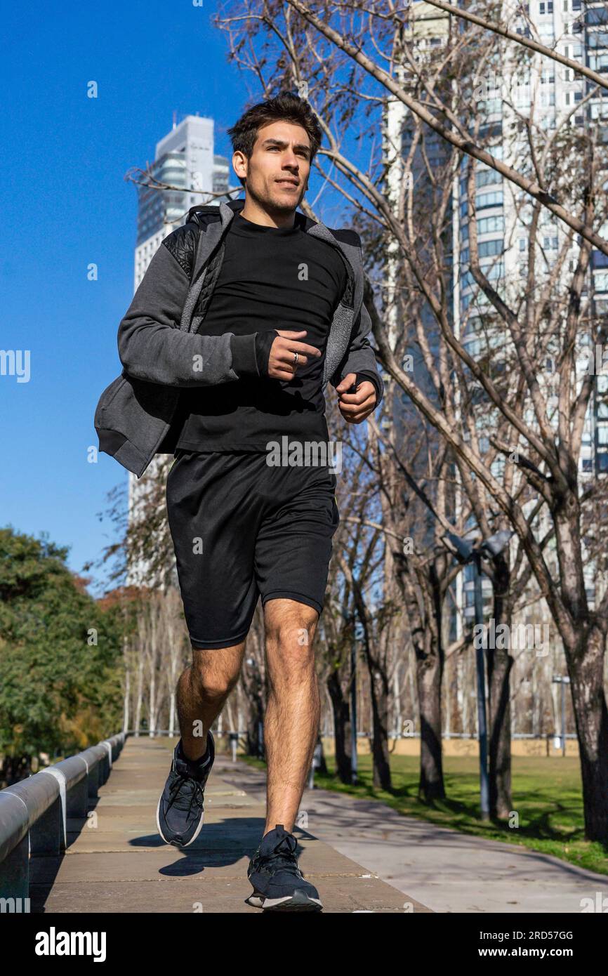 Ein motivierter, attraktiver Mann, der am grünen Park joggt Stockfoto