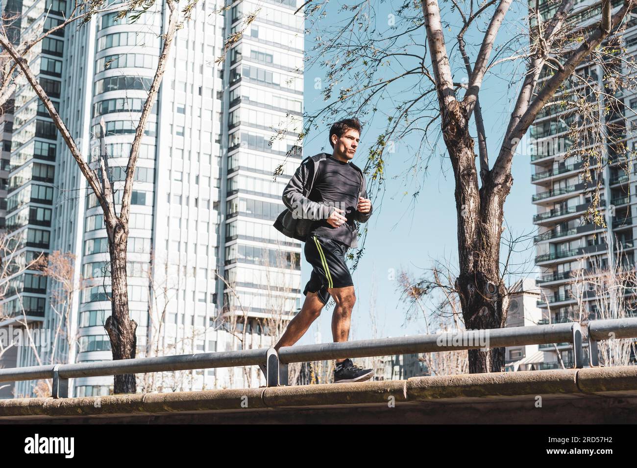 Seitenansicht eines motivierten, gutaussehenden Mannes, der am grünen öffentlichen Park joggt. Speicherplatz kopieren Stockfoto