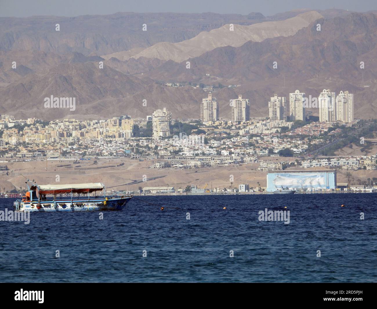 Touristenboote in den Gewässern des Roten Meeres (Golf von Akaba - Jordanien) und die Flagge und Gebäude der israelischen Besatzung in Palästina Stockfoto