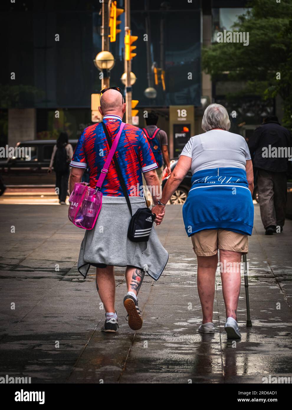 Foto von Senioren, die Händchen halten und draußen gehen. Rückansicht eines alten Paares, das Hand in Hand nach draußen geht. Straßenfoto, Reisefoto Stockfoto