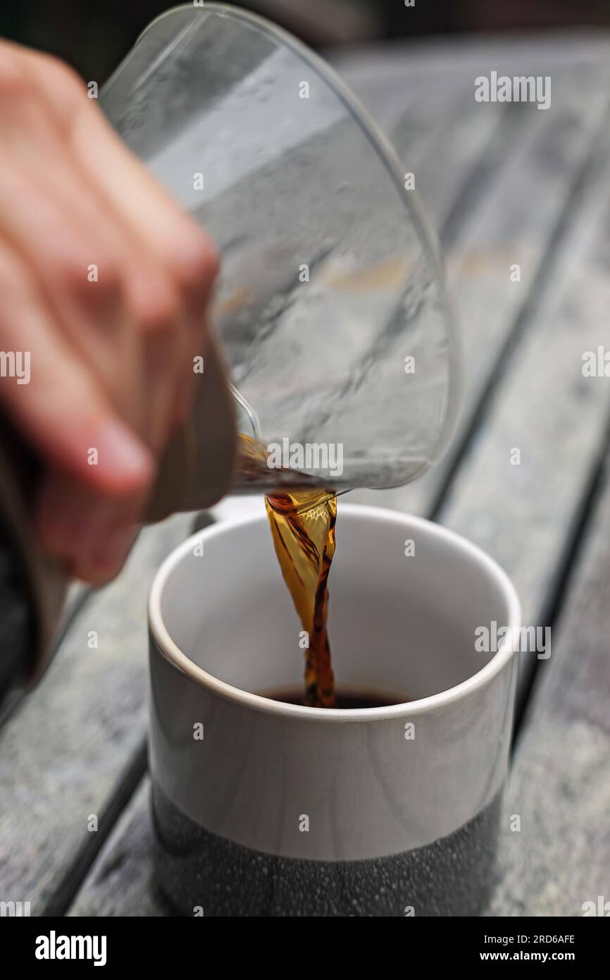 Nahaufnahme eines Mannes, der Kaffee per Hand in die Tasse portiert Stockfoto