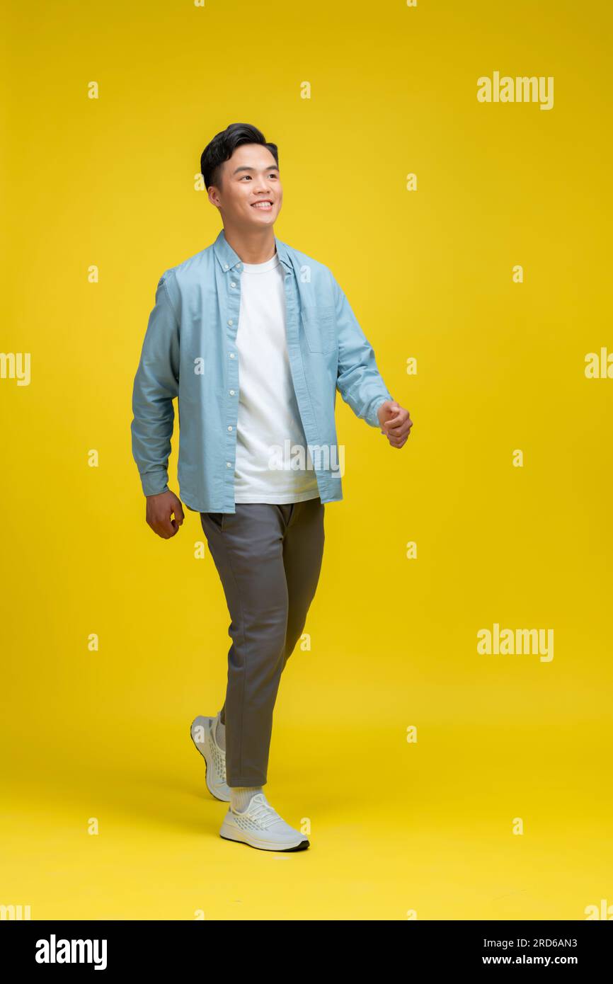 Ganzkörperfoto eines charmanten, glücklichen jungen Mannes, der leerer Raum aussieht, isoliert auf gelbem Hintergrund Stockfoto