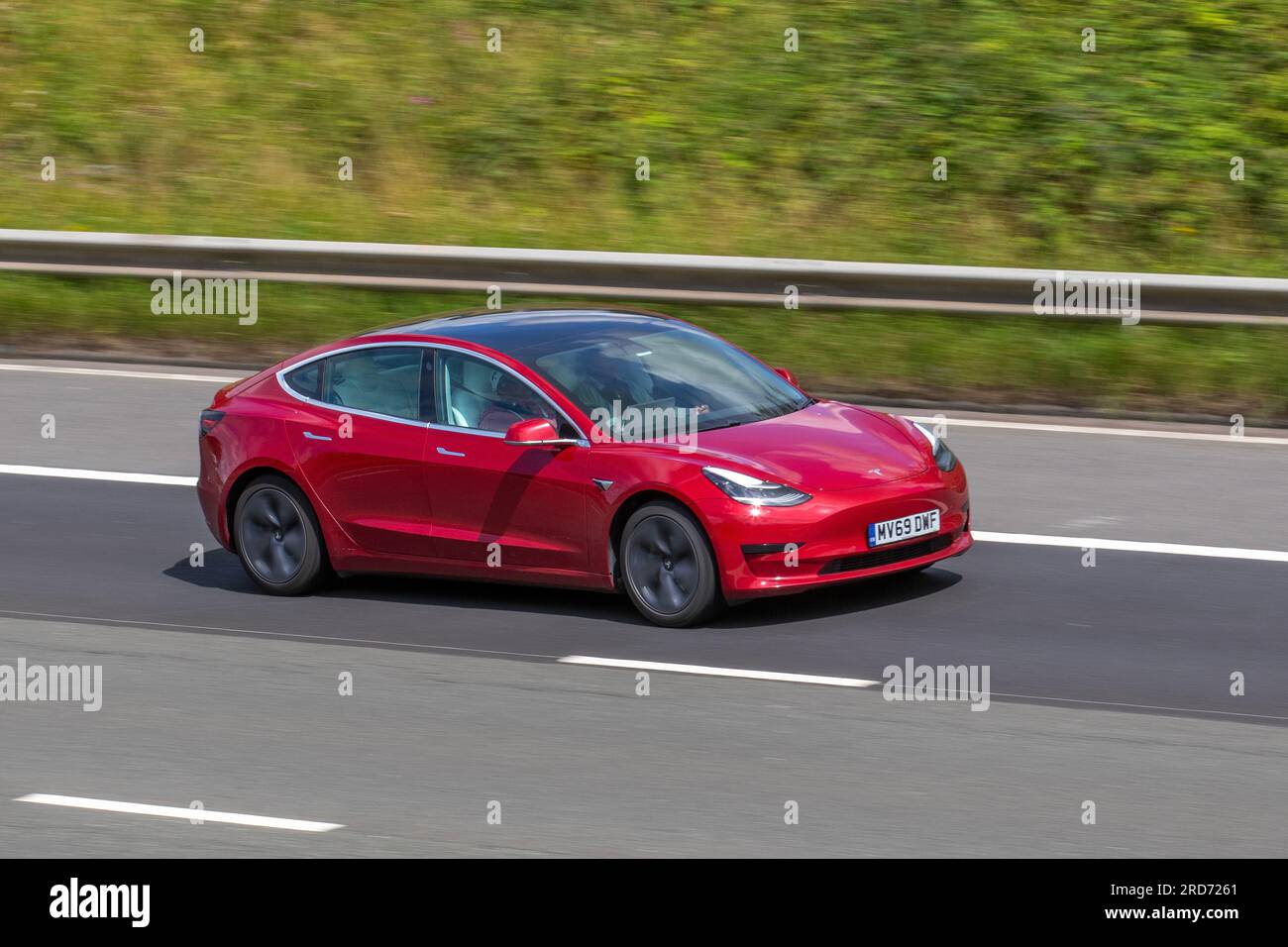2019 Red Tesla 3 Standard Range + Red Car Limousine Electricity 177 kW; Fahren mit hoher Geschwindigkeit auf der Autobahn M6 im Großraum Manchester, Großbritannien Stockfoto