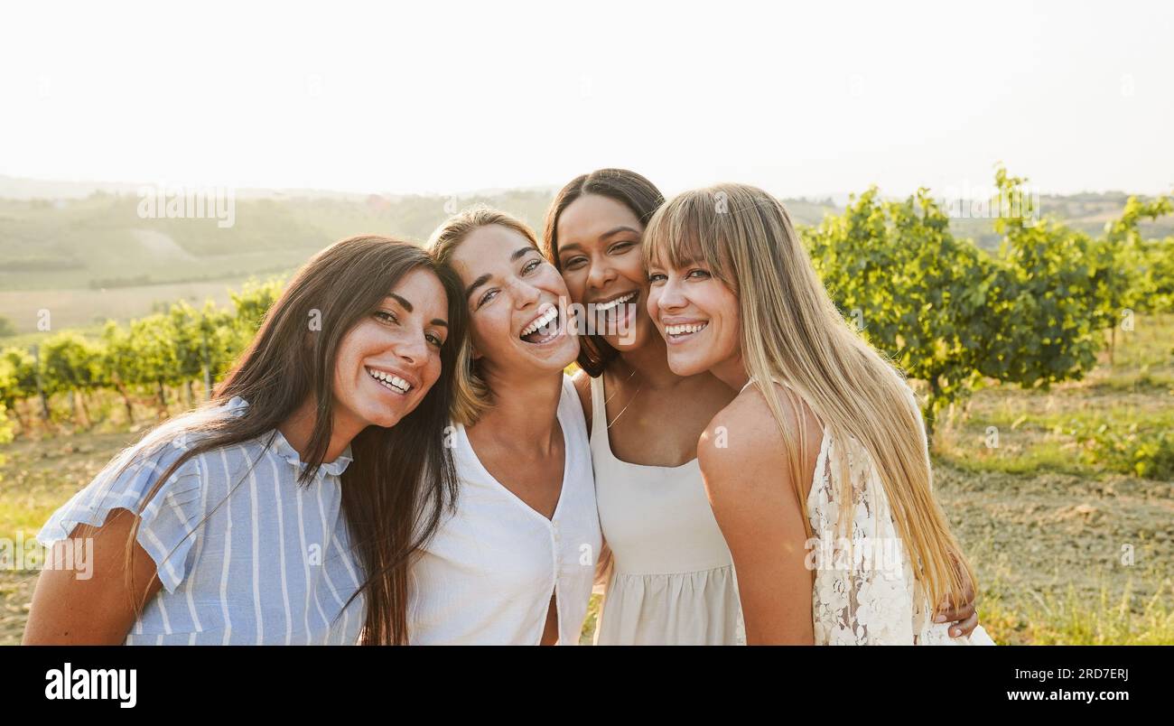 Gruppe von Freundinnen, die Spaß bei einer Sommerveranstaltung auf dem Land haben, mit Weinbergen im Hintergrund - Sommerurlaub, Party und Reisekonzept - Fokus auf Stockfoto