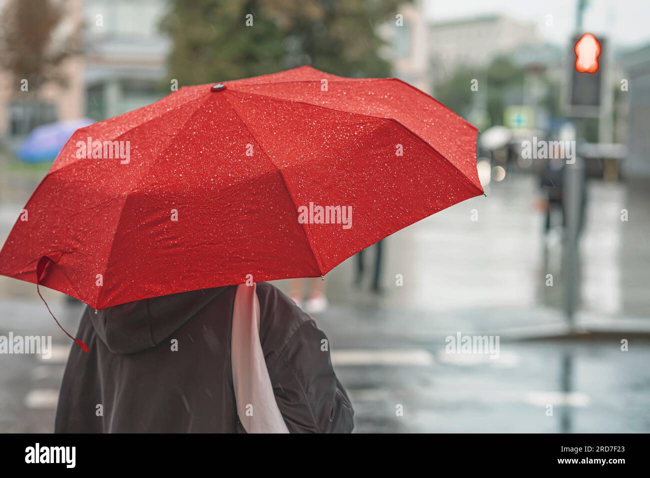 Abstraktes Mädchen unter rotem Schirm, moderne Stadt an regnerischen Abenden Stockfoto