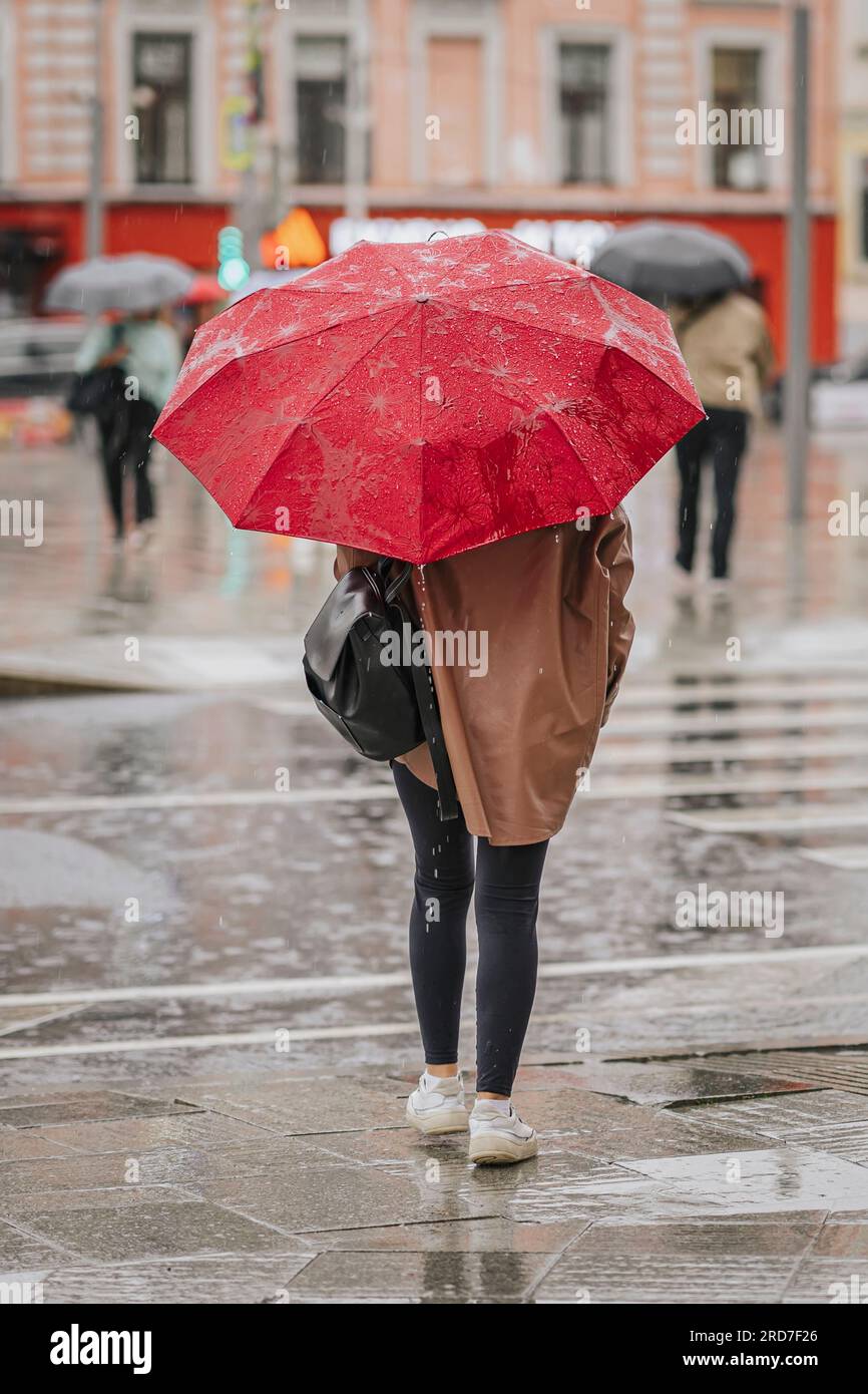 Abstraktes Mädchen unter dem Schirm, Rückblick, regnerischer Abend, Lifestyle in moderner Stadt, Herbstwetterkonzept Stockfoto