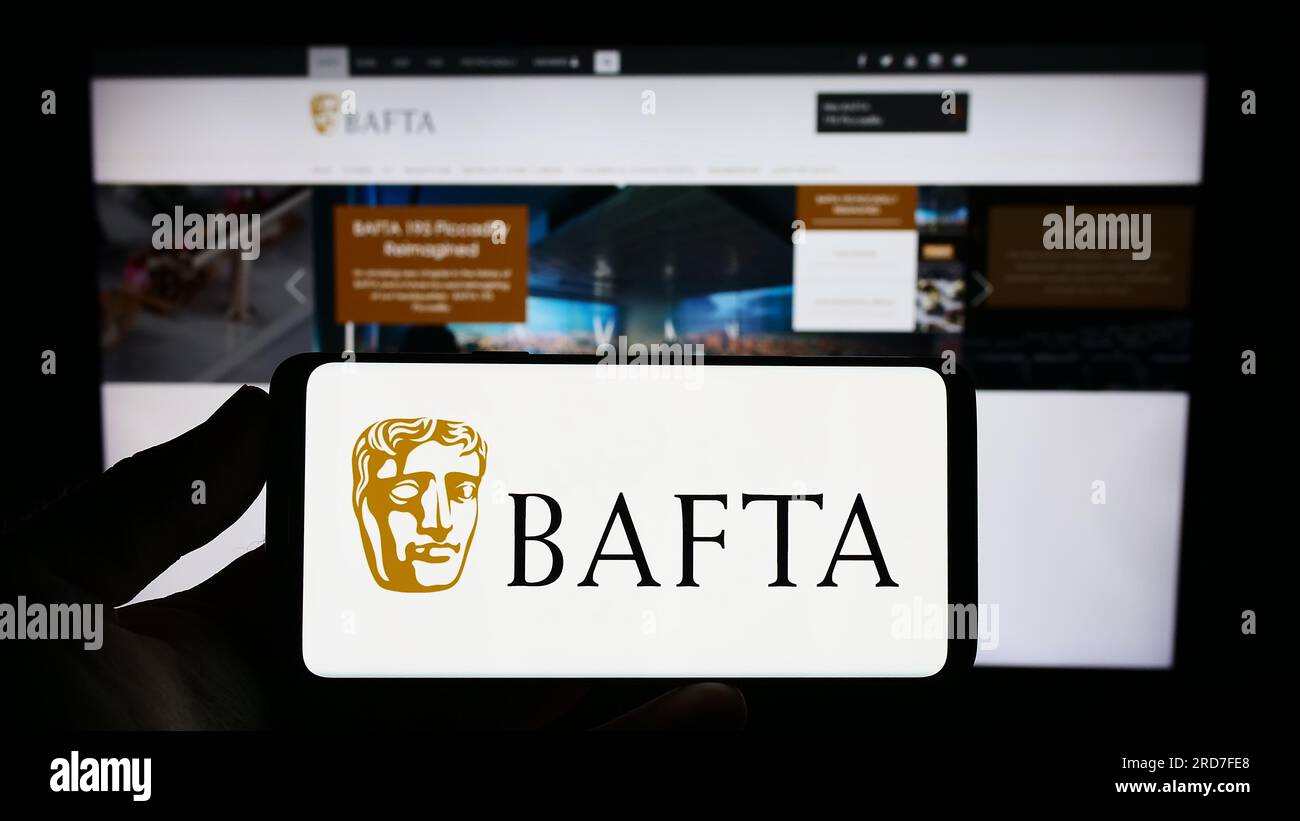 Person, die ein Smartphone mit dem Logo der British Academy Film Awards (BAFTA) auf dem Bildschirm vor der Website hält. Konzentrieren Sie sich auf das Display des Telefons. Stockfoto