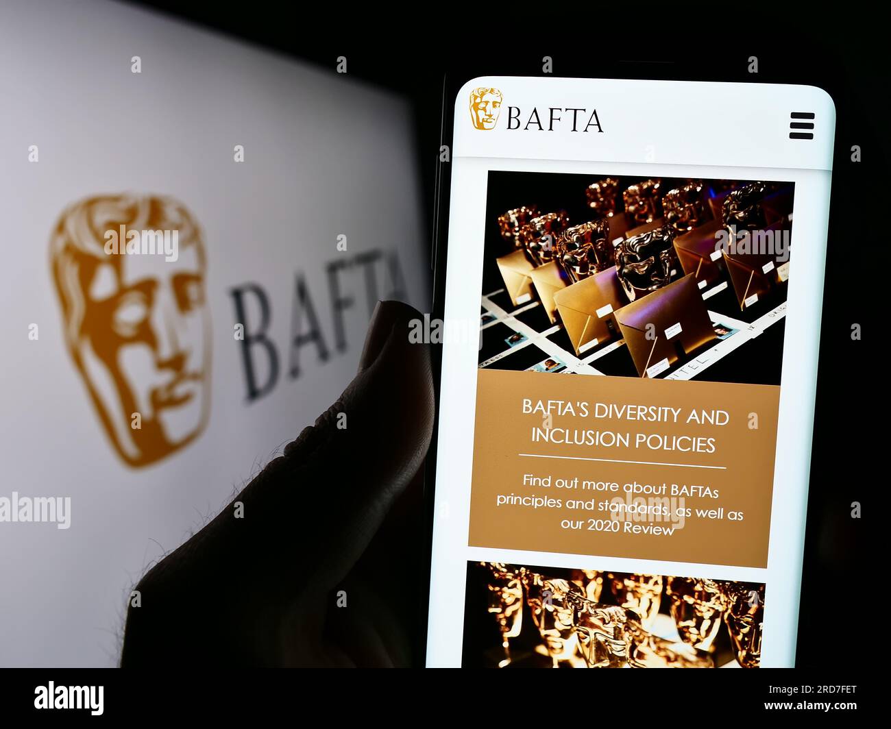 Person, die ein Mobiltelefon mit einer Webseite der British Academy Film Awards (BAFTA) auf dem Bildschirm vor dem Logo hält. Konzentrieren Sie sich auf die Mitte des Telefondisplays. Stockfoto