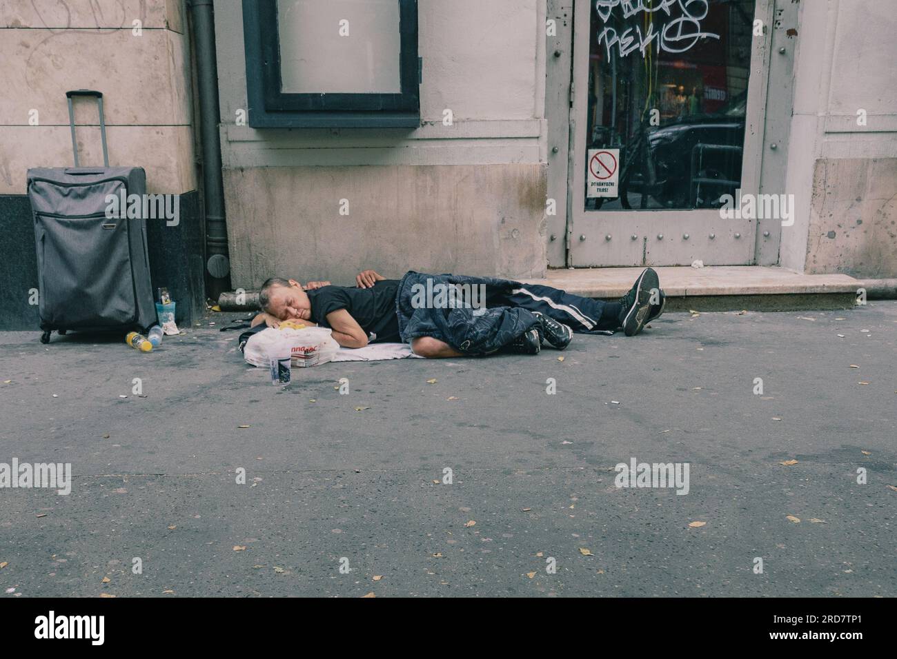 Zwei Obdachlose schlafen tagsüber auf der Straße. In Ungarn, insbesondere in Budapest, herrscht anhaltende Besorgnis über Obdachlosigkeit. Aufgrund der hohen Inflation ist die Zahl der Menschen, die auf den Straßen leben, in der Stadt gestiegen. Faktoren wie Armut, Arbeitslosigkeit, psychische Gesundheit und Mangel an bezahlbarem Wohnraum tragen zu dem Problem bei. Die ungarische Regierung und die lokalen Behörden haben verschiedene Maßnahmen zur Bekämpfung der Obdachlosigkeit ergriffen. Dazu gehören die Bereitstellung von Notunterkünften, soziale Dienste und Programme zur Wiedereingliederung in die Gesellschaft. Nicht- Stockfoto